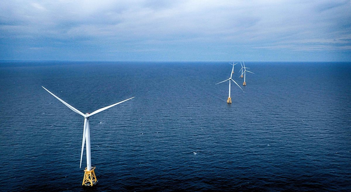 Aerial view of the Block Island Wind Farm: five turbines standing on yellow four-leg jacket foundations in open water