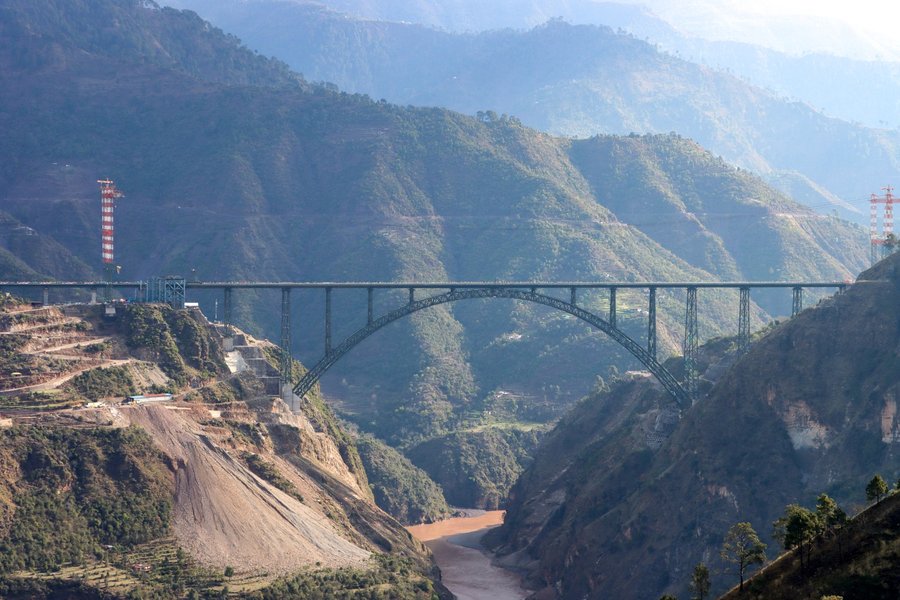 The Chenab Rail Bridge spanning the deep gorge of the Chenab River in Reasi district, Jammu and Kashmir, India, showing the steel arch and approach spans against the surrounding mountains