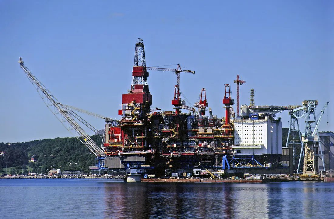 The Gullfaks A concrete gravity-base platform under completion at the Kvaerner yard in Stord, Norway, showing the Condeep shaft-and-cell design with tower cranes alongside