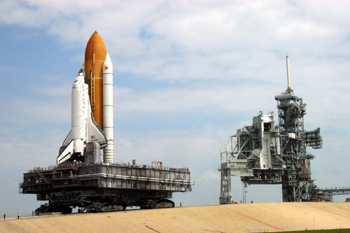 A crawler-transporter carrying Space Shuttle Discovery on its mobile launcher platform up the ramp towards Launch Pad 39B