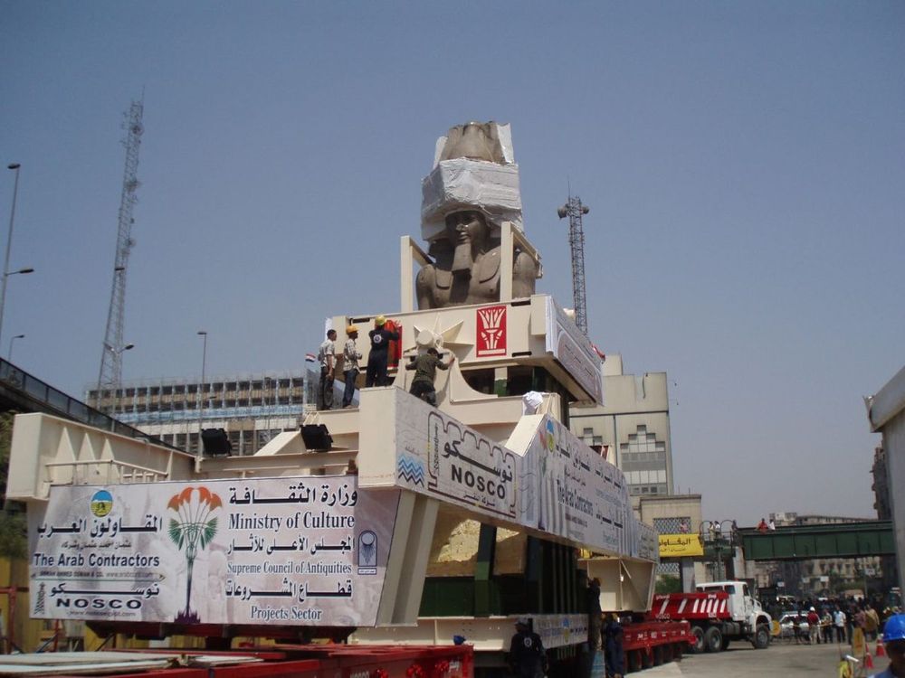 The Ramses II colossus wrapped and braced inside a cream steel transport frame on a multi-axle trailer in central Cairo, August 2006, with workers on the frame