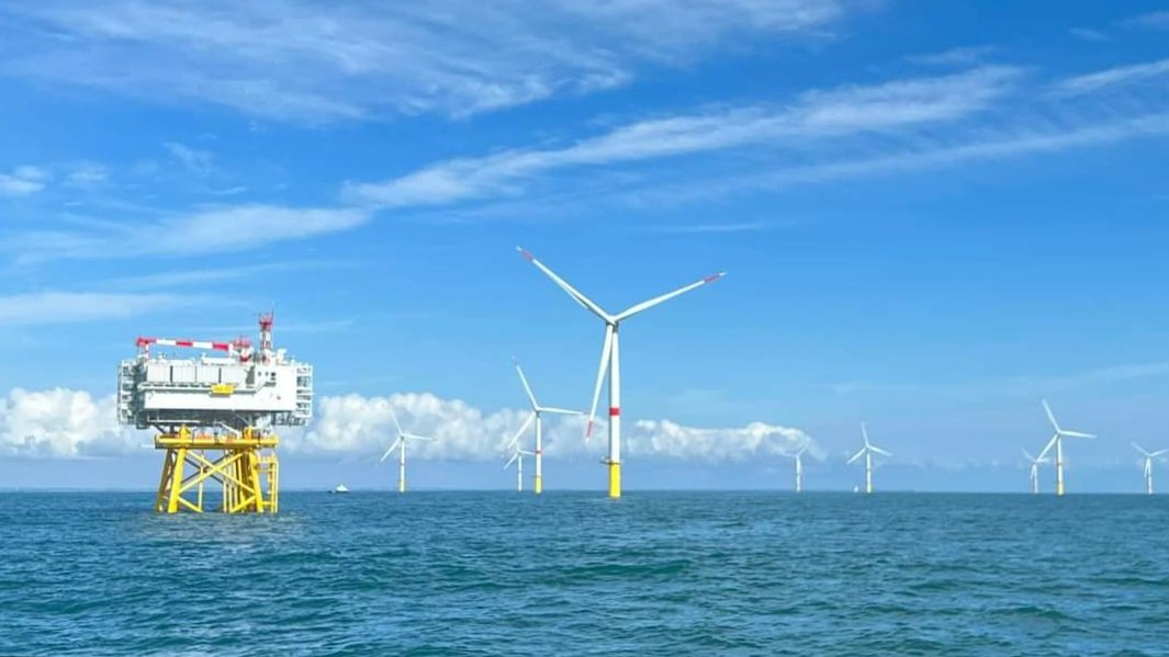 Saint-Nazaire offshore wind farm: the offshore substation on a yellow jacket foundation, with monopile-founded wind turbines beyond, Banc de Gu&eacute;rande, September 2023
