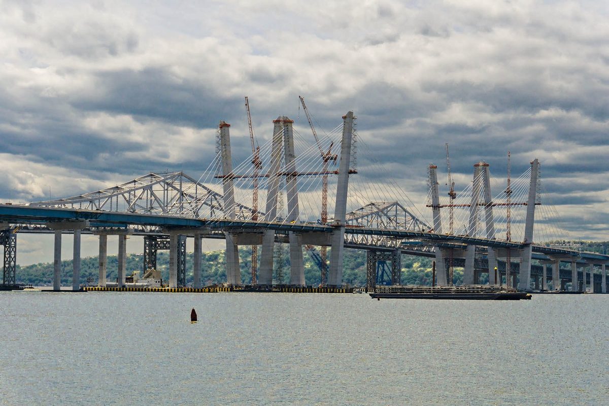 The old Tappan Zee Bridge&rsquo;s steel truss with the new twin spans under construction behind it, seen across the Hudson River in May 2017