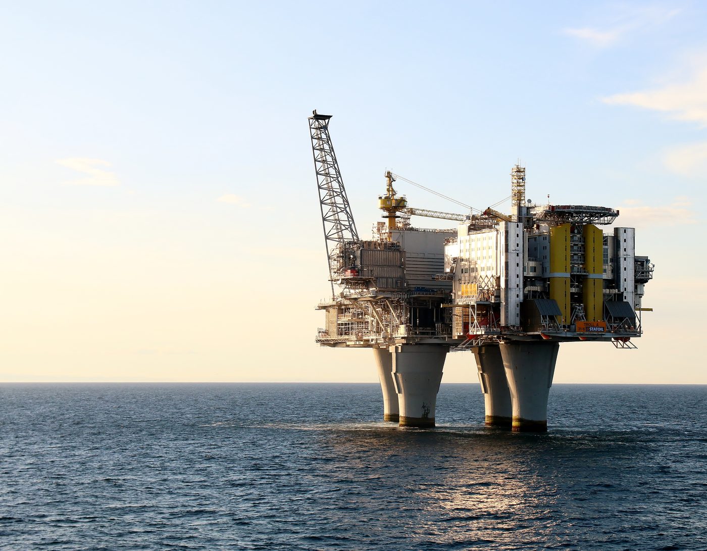 Troll A concrete gravity-base platform standing in the North Sea at sunset, its four concrete legs rising from the water to the topside deck