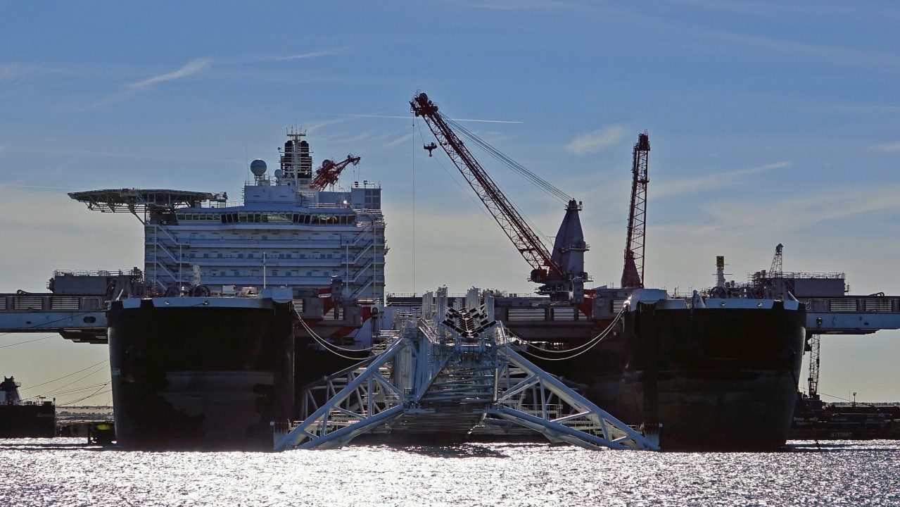 The twin-hulled heavy lift vessel Pioneering Spirit moored at Maasvlakte 2, Rotterdam, with its lifting beams visible in the slot between the two hulls